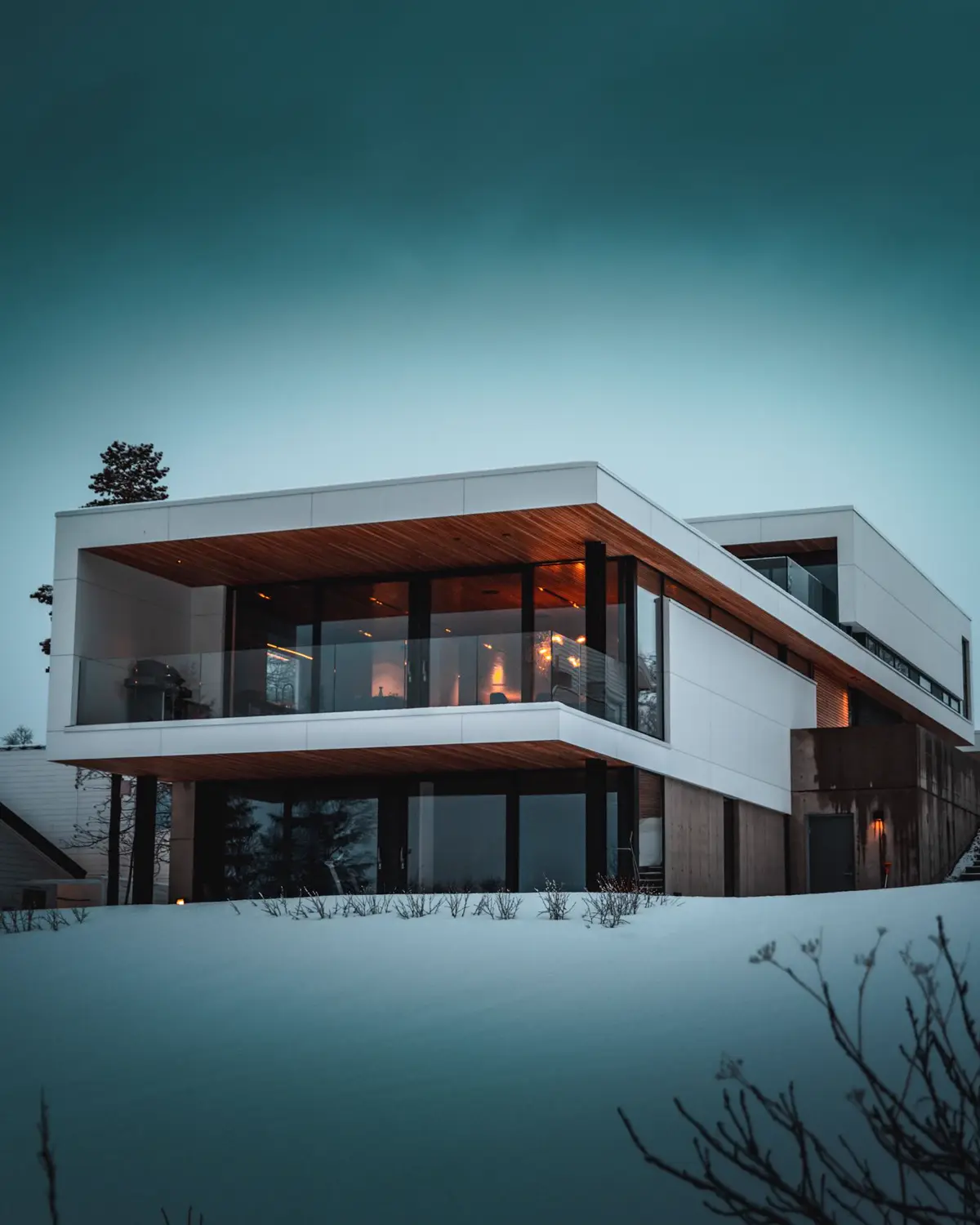 Casa moderna con volado de madera y vidrio al atardecer